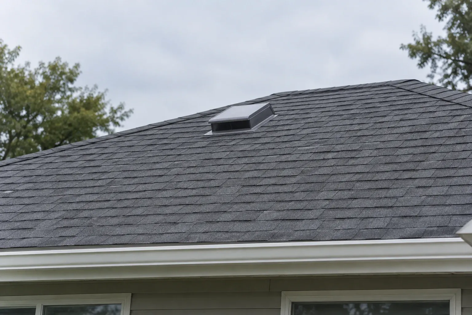 Low-profile metal attic vent on a gray asphalt-shingle roof.