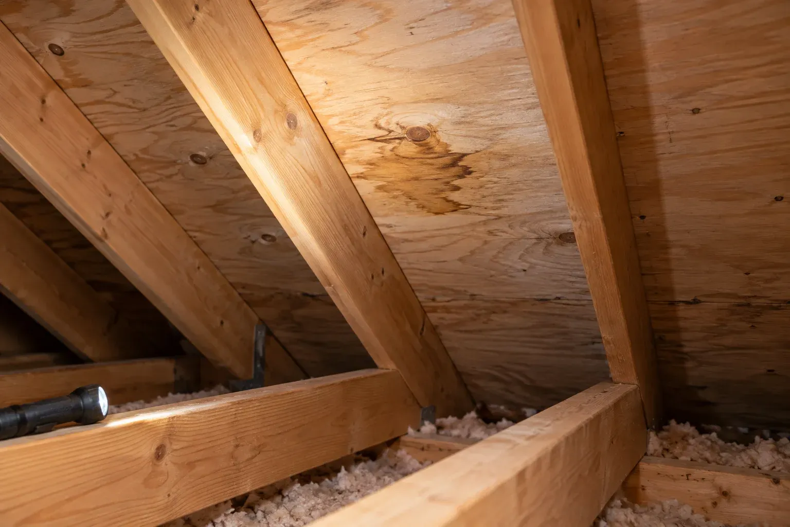 Localized staining on attic roof sheathing, illustrating concealed conditions that may need clarification in a repair quote.